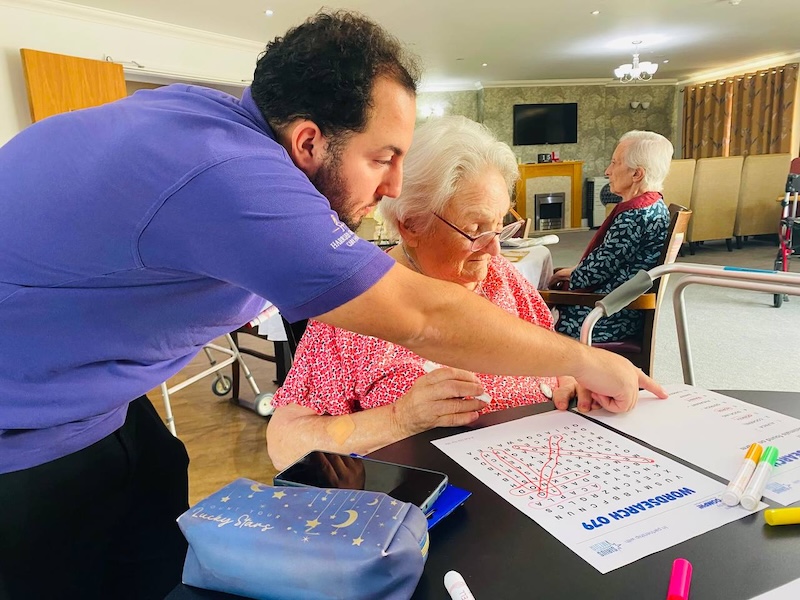 resident doing a wordsearch with carer