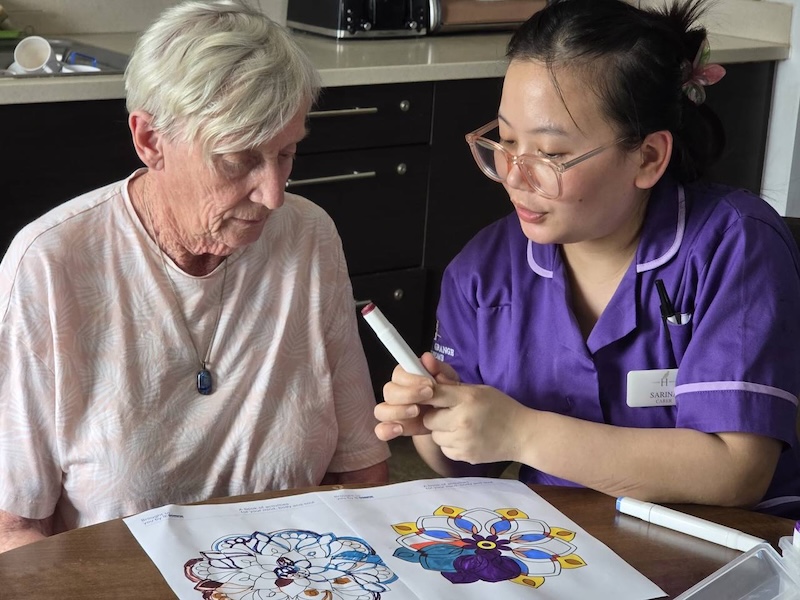 resident doing colouring with a carer