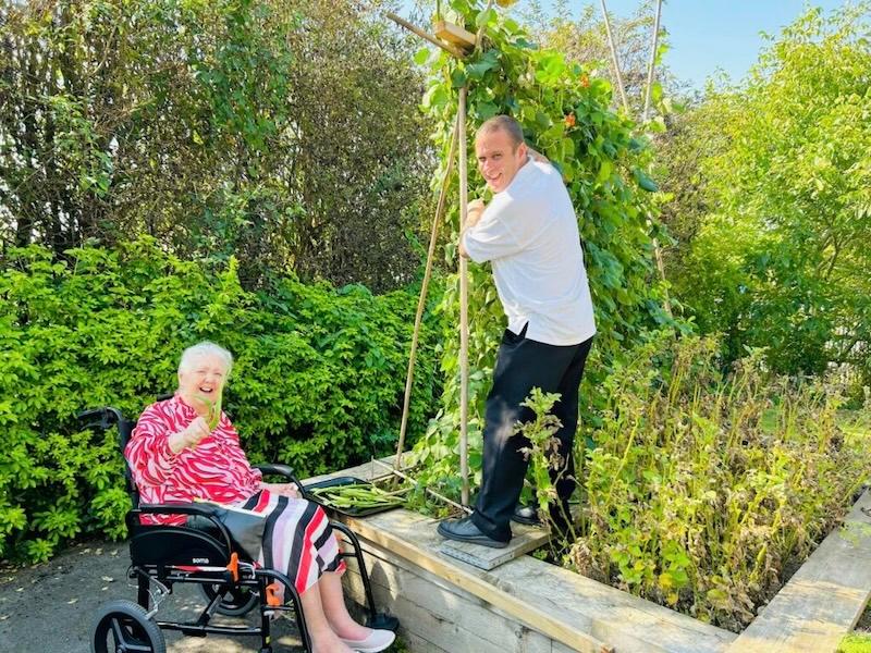 resident and team member outside getting produce for the dining experience