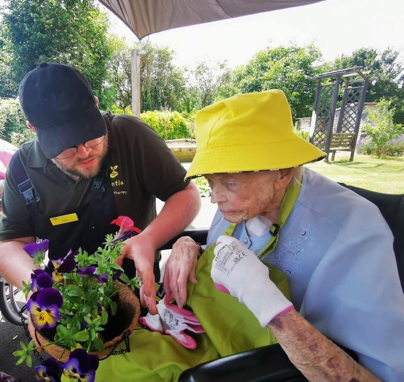 resident sat in the garden potting plants with our volunteer