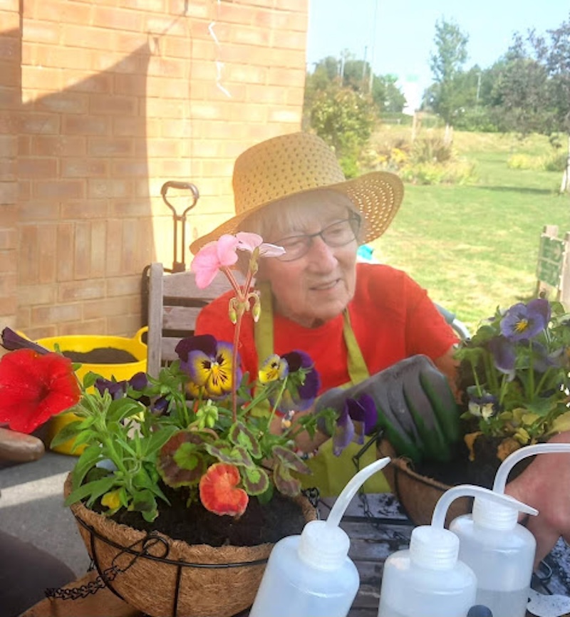 resident surrounded by flowers whilst doing gardening outside