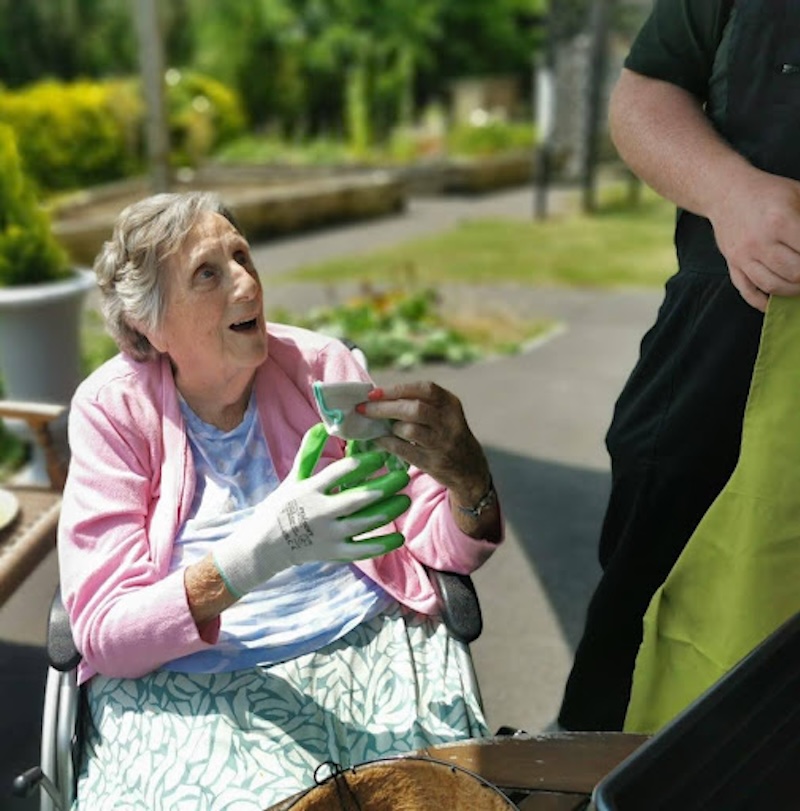 resident with gardening tools sat in the garden