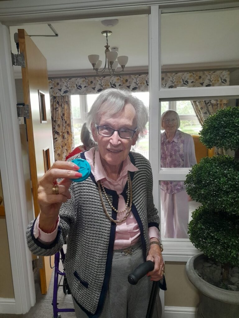 one of our residents smiling with a blue token in her hand