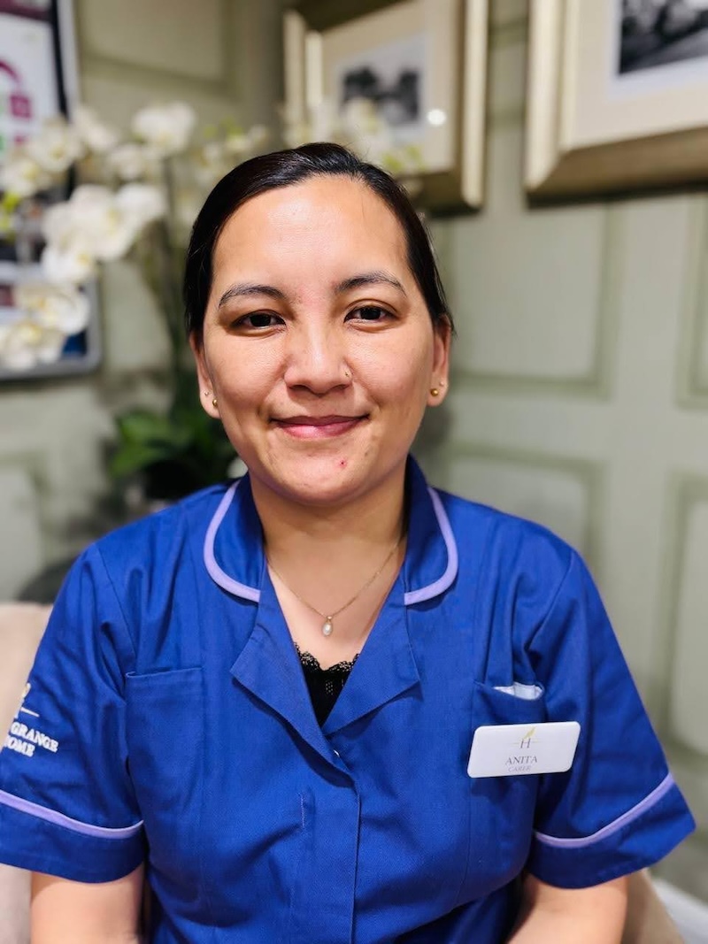 Woman with born hair sat in an armchair wearing a purple care assistant uniform