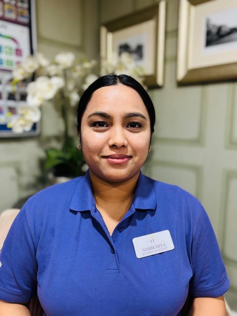 Samikshya Nepali one of our housekeeping team sat in an armchair smiling wearing a purple top