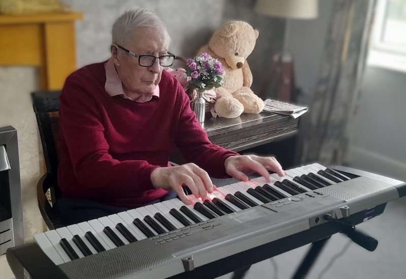 elderly man sat down playing the keyboard