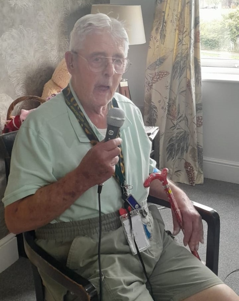 older man sat down singing in a lounge