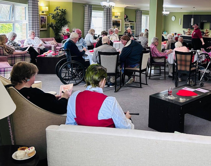 a lounge full of residents and visitors sat down enjoying a game of valentines bingo