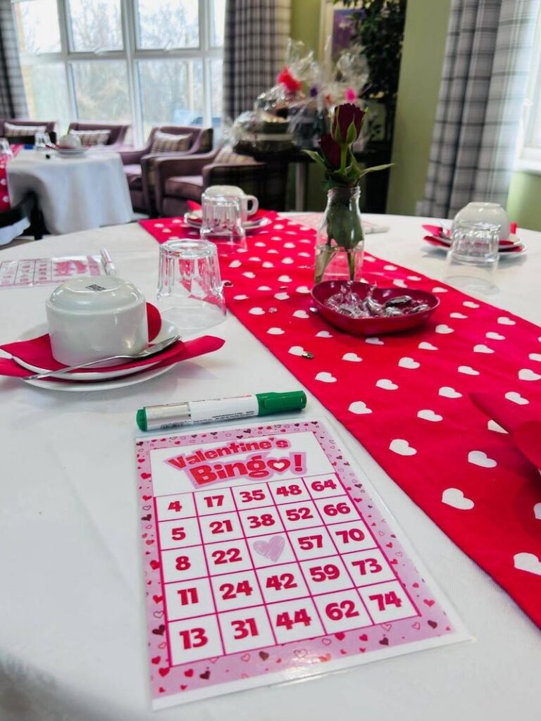 valentines themed bingo card laid out on a table with red and white decorations