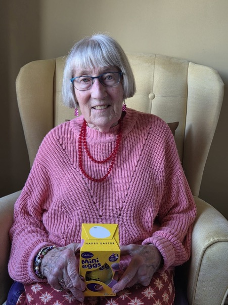 older lady wearing glasses holding a mini eggs easter egg