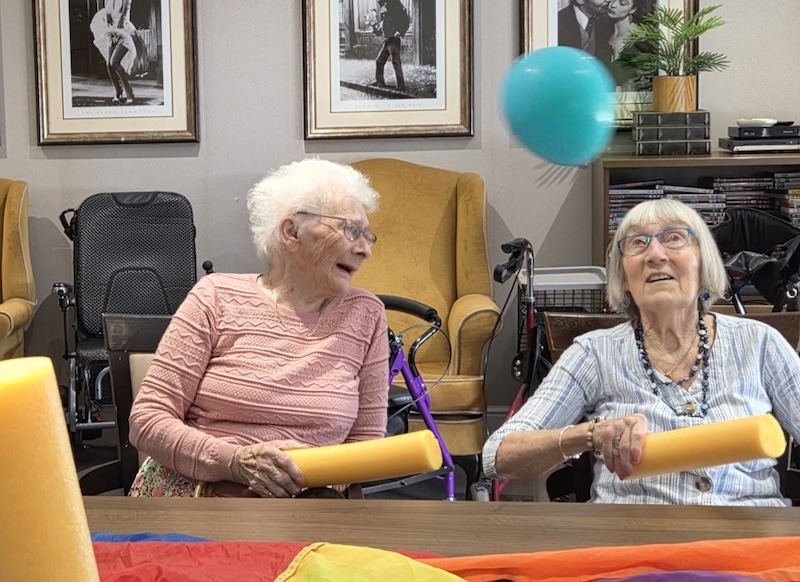 2 residents laughing playing balloon tennis