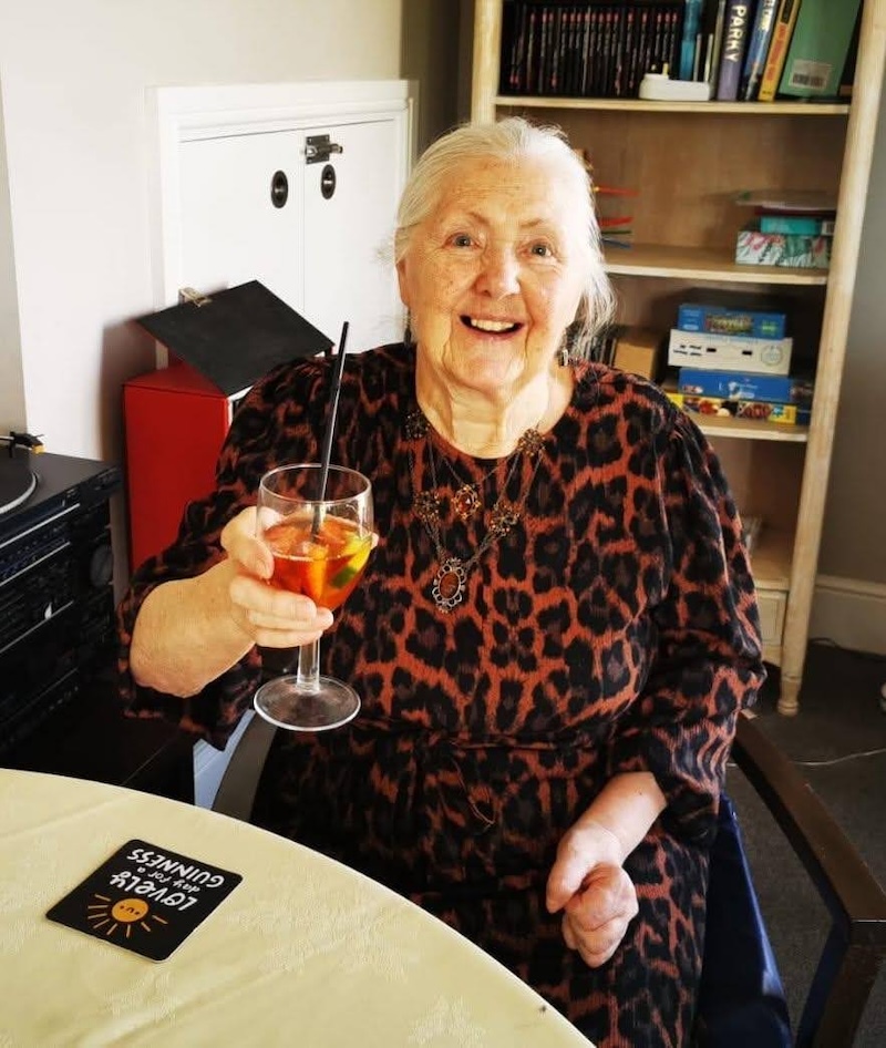 female resident sat with a drink in her hand smiling