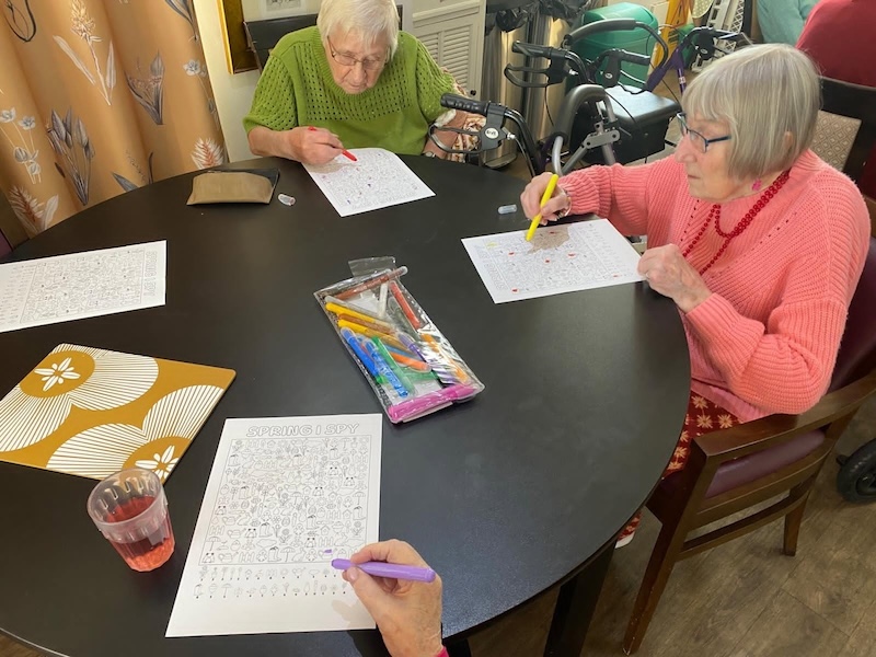 a group of residents sat around a table doing some colouring with pens