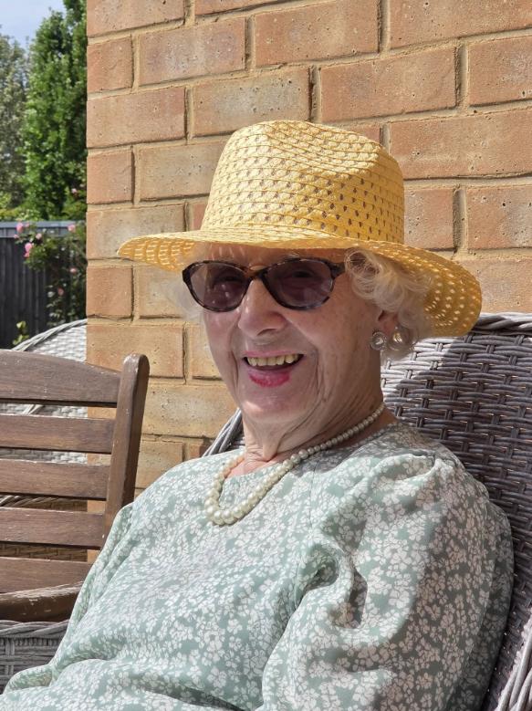 older lady in sunglasses and a sunhat smiling
